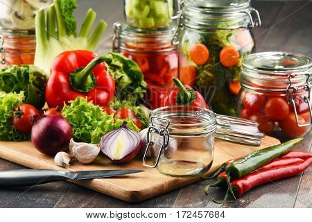 Jars With Marinated Food And Raw Vegetables On Cutting Board