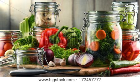 Jars With Marinated Food And Raw Vegetables On Cutting Board