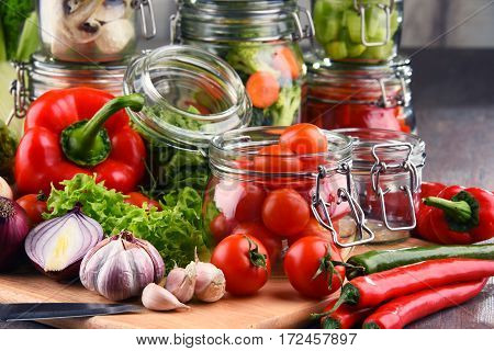 Jars With Marinated Food And Raw Vegetables On Cutting Board