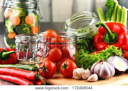 Jars With Marinated Food And Raw Vegetables On Cutting Board