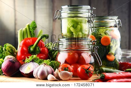 Jars With Marinated Food And Raw Vegetables On Cutting Board