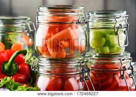 Jars With Marinated Food And Raw Vegetables On Cutting Board
