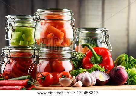 Jars With Marinated Food And Raw Vegetables On Cutting Board
