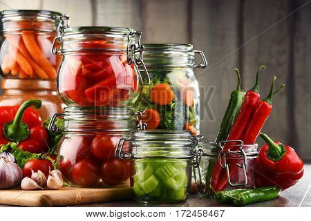 Jars With Marinated Food And Raw Vegetables On Cutting Board