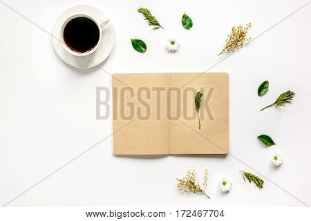 Flower petals, cup of coffee and brown craftpaper copybook on table background top view mock up