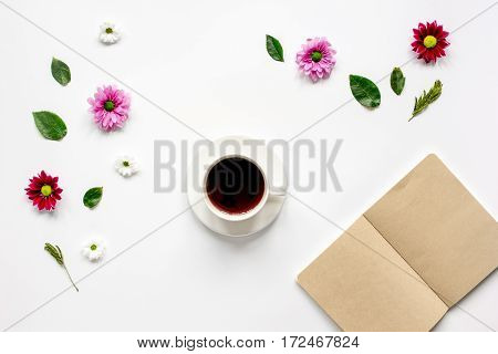 Froral flat lay with cup of coffee and craft notepaper on white background top view mockup