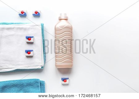 Bright towels pile with washing powder in laudry set on white table background top view mock-up