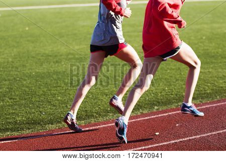 Two girls training for speed together on a red track
