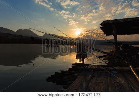 Shooting backlit atmosphere morning of fishing fishing rods leaning on bamboo while the sunrise. On the floating house Khao Leam national park Sangkhlaburi Kanchanaburi Thailand.