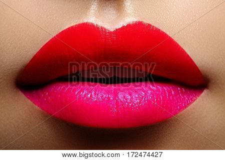 Cosmetics makeup and trends. Bright lip gloss and lipstick on lips. Closeup of beautiful female mouth with red and pink lip makeup. Beautiful part of female face. Perfect clean skin