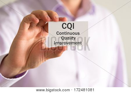 Businessman Holding A Card With Text Cqi Continuous Quality Improvement