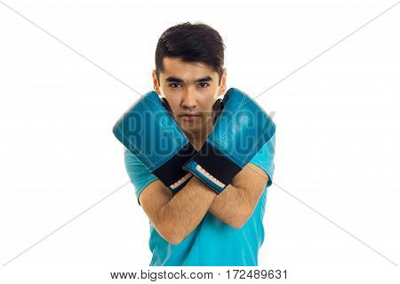 young guy stands folded arms in blue boxing gloves is isolated on a white