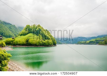 Beautiful emerald mountain lake Lungern in Switzerland under low clouds