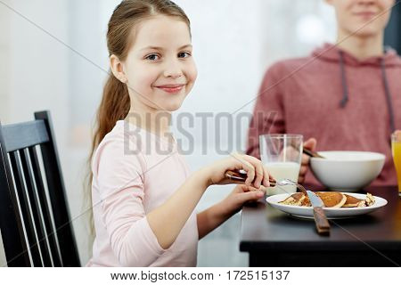 Happy girl eating tasty pancakes in the morning