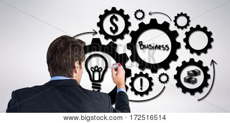 Rear view of businessman standing and writing against grey background