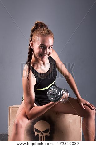 Young confident woman doing biceps curl exercise with dumbbells in fitness center. Slim girl training in the gym with dumbbells