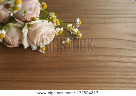 Rose and daisy bouquet on wooden background