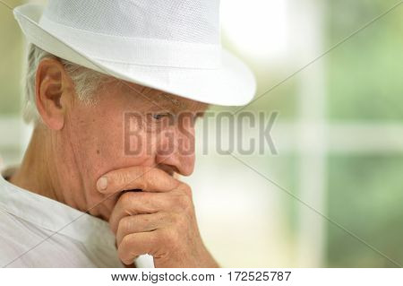 portrait of pensive senior man in hat