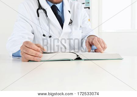 Doctor reading a Medical Book in Office Desktop. Health care Medical and Pharmacy Concept.