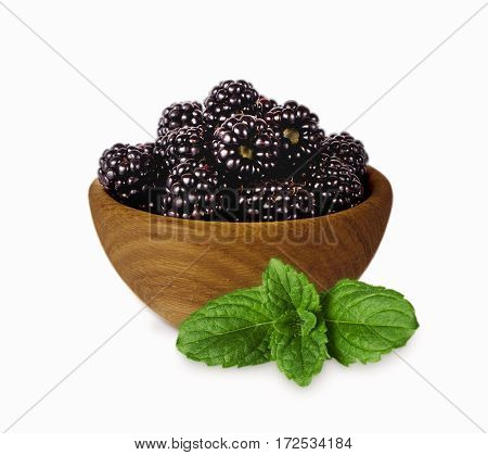 Blackberries on a wooden bowl isolated on white. Ripe blackberries with mint close-up. Background berry. Sweet and juicy blackberries with copy space for text.