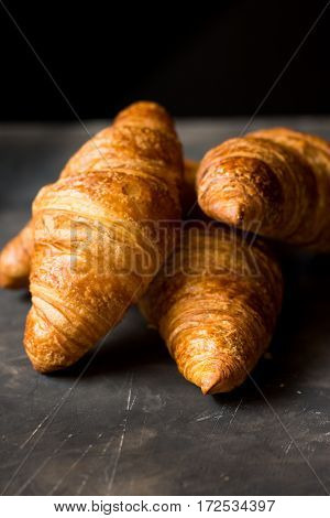 Heap of freshly baked croissants on black background golden delicious crustclose up minimalistic style