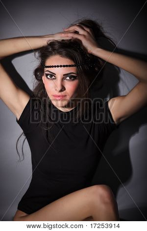 Mladý štíhlý Glamour Lady s dlouhými vousy, oblečený v černých šatech Combi sedí na podlaze, tmavě klíč