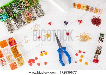 Making handmade jewelry. Boxes with beads pliers threads equipment and accessories for handmade on wooden table. Process of needlework. Top view