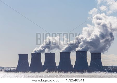 Cooling towers of a Nuclear energy station  or NPP with thick smoke on blue sky background. Copy space for text