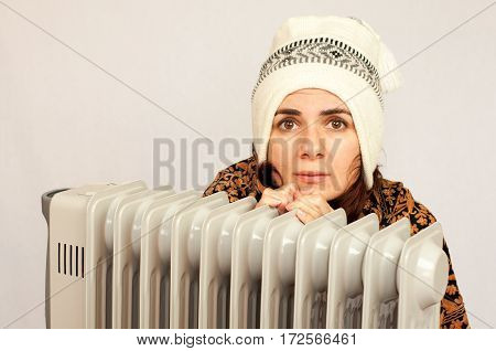Young woman freezing near the heater studio shot