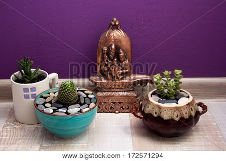 lingam and succulents in ceramic pots on purple background wall.