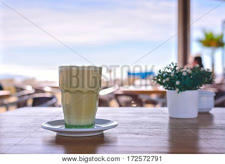 Latte at the beach. Iced Coffee Frappuccino or frappe in a tall glass. Sea view background Barcelona Catalunya Spain