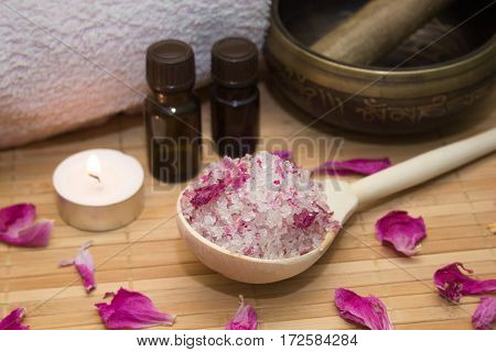 homemade body scrub from sea salt and rose petals and peony Tibetan bowlcandlepink towel and aroma oil on a straw Mat. Spa concept