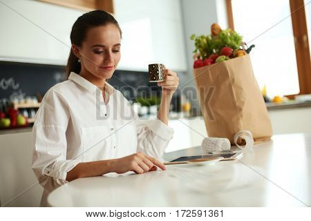 Young woman planning expenses and paying bills on her kitchen