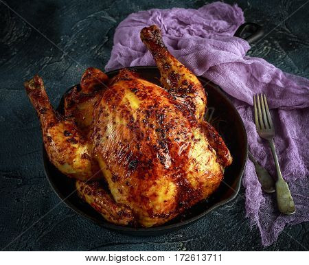 Organic cornfed free range oven baked chicken in rustic pan with lemon slices and rosmary.