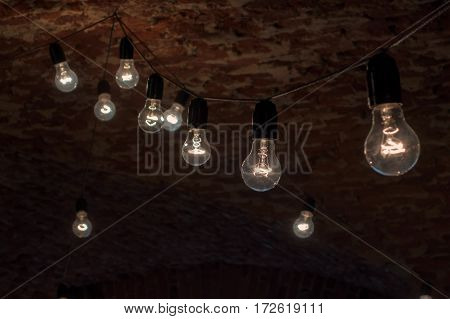 Several light bulbs hanging and shines on the background of an old brick ceiling