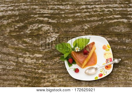 Delicious homemade Flan dessert or creme caramel dessert with mint. Slice of Milk Pudding over a wooden table. Brazilian Flan with strawberries. Panna cotta dessert with caramel sauce.