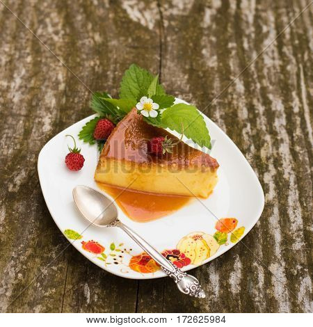 Slice of Milk Pudding with mint and strawberries over a wooden table. Brazilian Flan. French creme caramel dessert or flan with ingredients at the background. Custard pudding