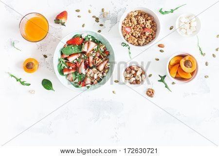 Breakfast with muesli strawberry salad fresh fruit nuts on white background. Healthy food concept. Flat lay top view