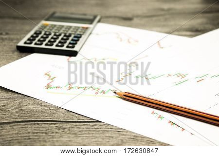 calculator and pencil on graffica the Dow Jones on forex market at grey table