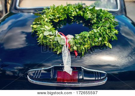 green wreath with silk ribbon lying on the car
