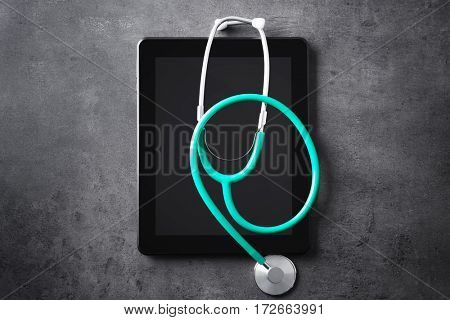 Stethoscope and tablet pc on grey table