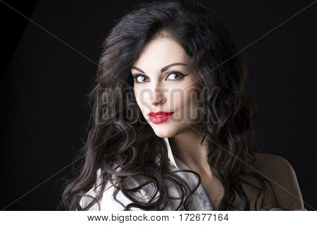 Closeup portrait of young brunette woman in white shirt, dark studio wall background