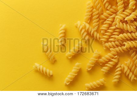 Fusilli pasta spirals on yellow background