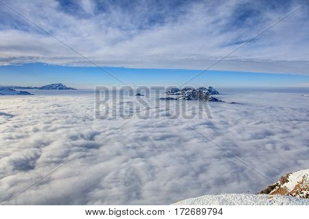 Summits of the Swiss Alps rising from sea of fog - wintertime view from Fronalpstock mountain in the Swiss canton of Schwyz.