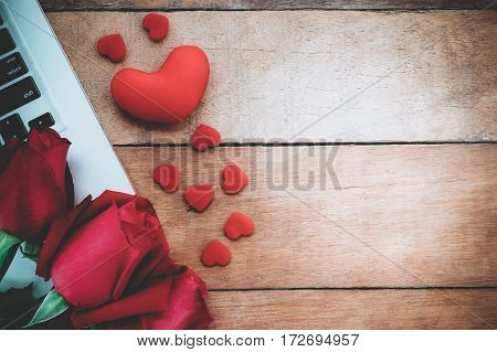 Red roses laptop computer and heart on wooden background with copy space.Valentines Day background concept Wedding day.Top view vintage tone