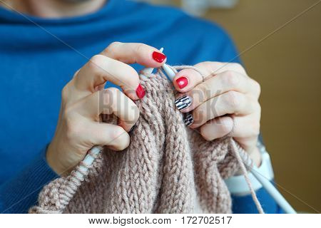 Hands of knitting woman with red manicure, close up view, noface