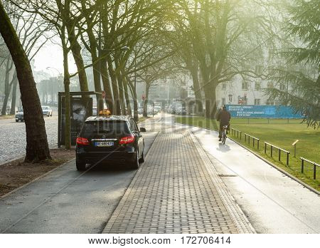 STRASBOURG FRANCE- FEB 2 2017: Mercedes-Benz taxi van exiting special taxi parking near the European PArliament bus station - cyclist biking on special lane
