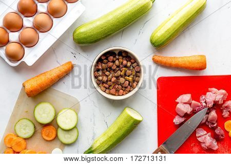 Dogfood set with cut fresh vegetables and knife on white kitchen table background top view