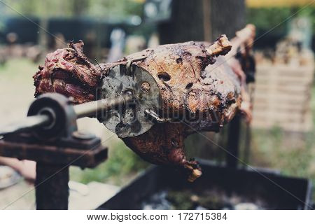 Barbecue picnic at country fair. Whole lamb roasted at spit. Grill, big piece of meat at rolling skewer. Street vendor bbq food. Catering concept