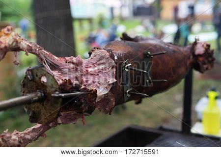 Barbecue picnic at country fair. Whole lamb roasted at spit. Grill, big piece of meat at rolling skewer. Street vendor, professional cooking bbq food. Catering concept